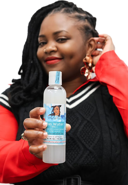 Black Woman with locs holding a bottle of  Natty By Nayee Corp Ras Water Step 1 in front of her.