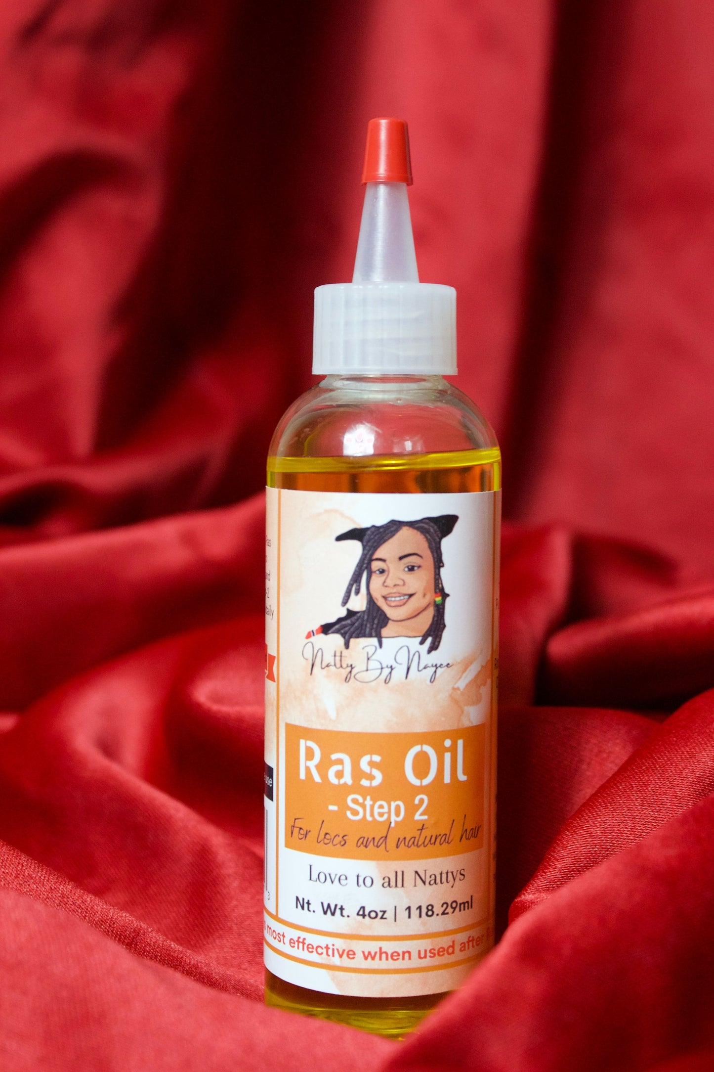 An image of Natty By Nayee Corp Ras Oil Step 2 on-top of a red velvet fabric.