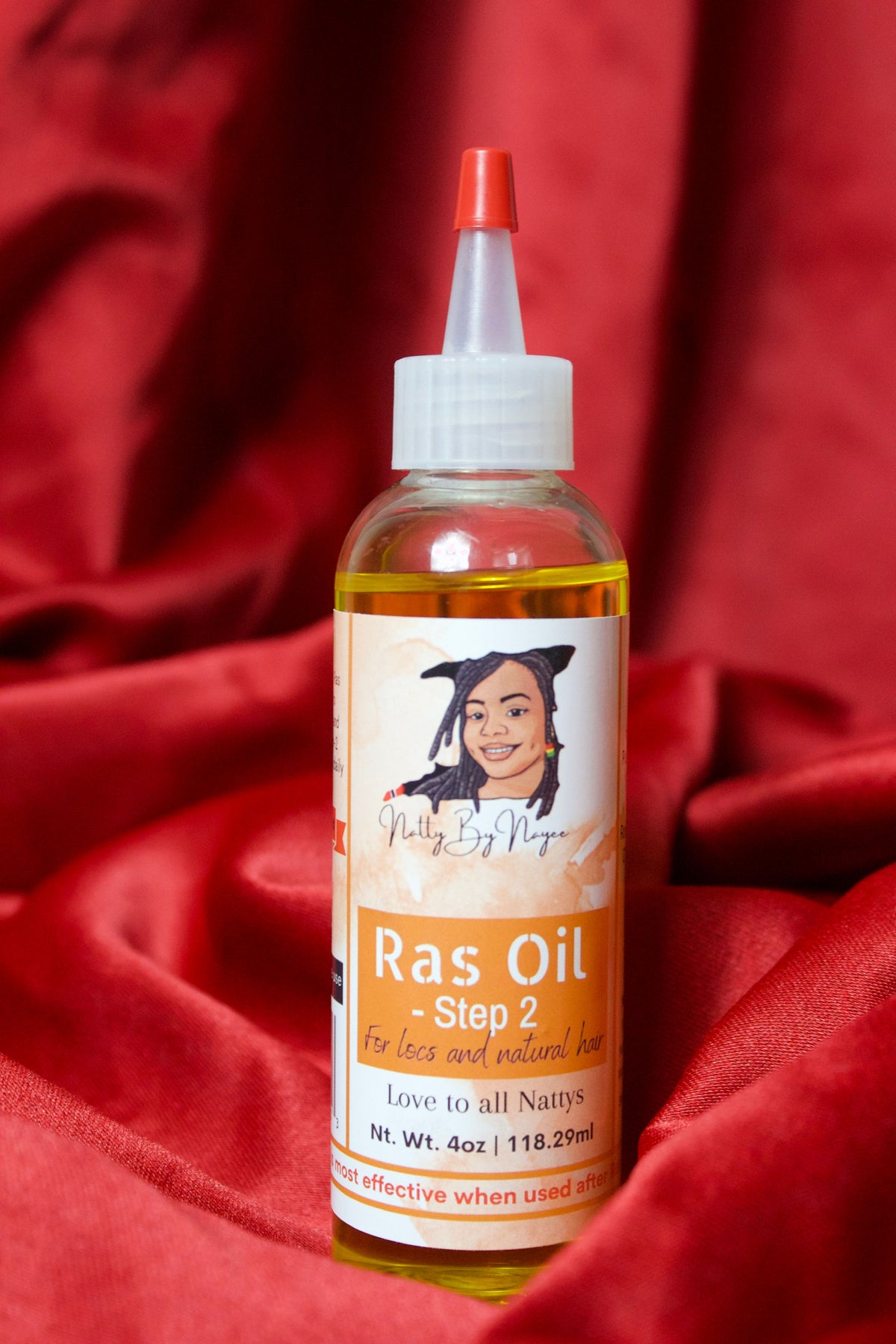 An image of Natty By Nayee Corp Ras Oil Step 2 on-top of a red velvet fabric.