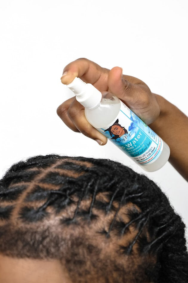 Person using a Natty By Nayee Corp Ras Water step 1 product to mist their hair with a white background